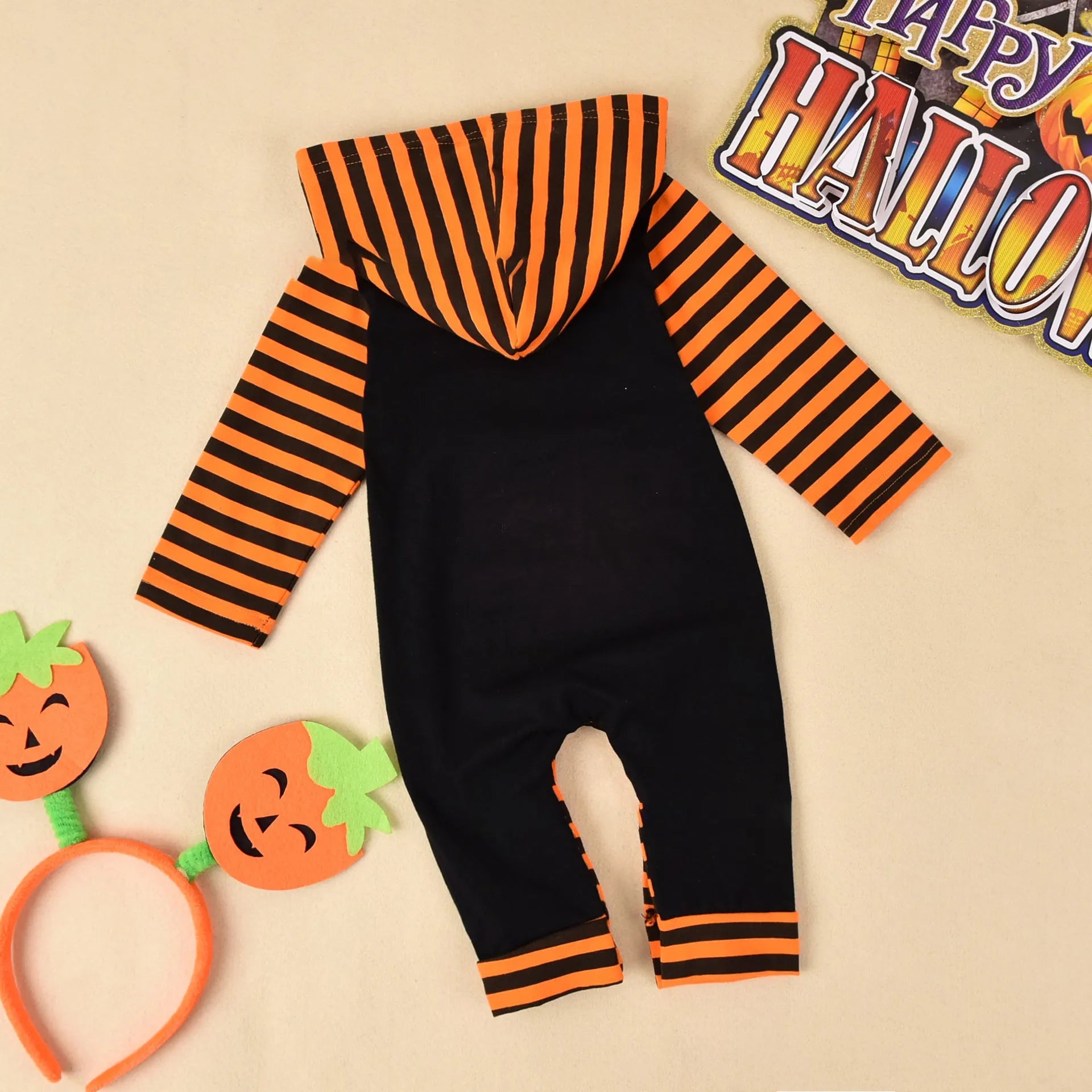 Black or brown cotton Halloween romper with long sleeves and a hood, laid flat.