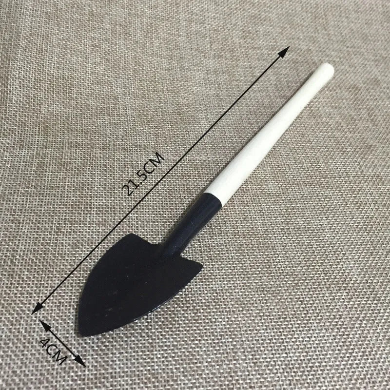 A succulent gardening tool set showing a mini watering can, bucket, tweezers, drip kettle, shovel, rake, and brush on a table.