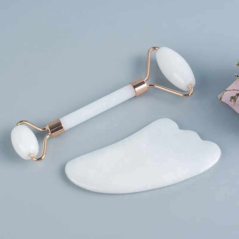 White jade facial roller set with double-headed roller claw and scraping board on wooden surface
