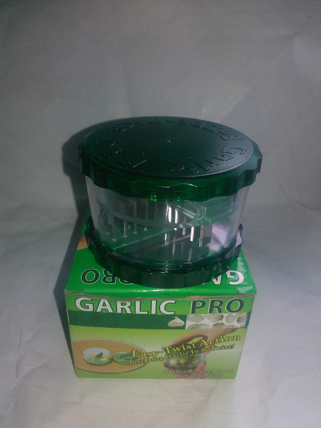 Green transparent plastic garlic peeler kitchen gadget on a countertop.