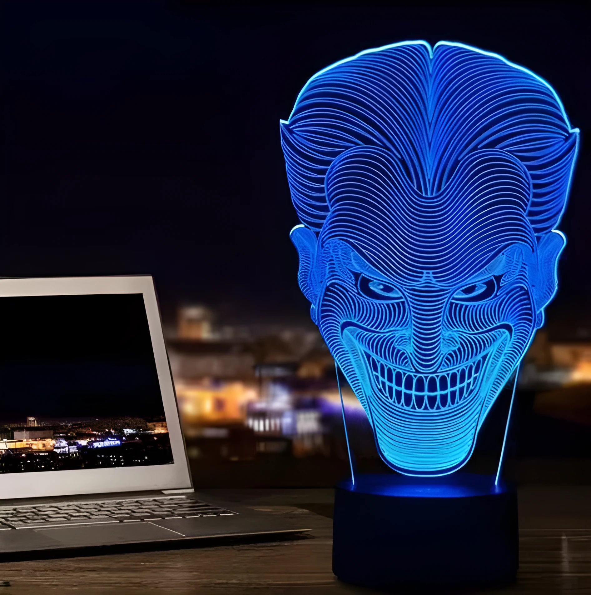 A 3D LED table lamp displaying multiple colours, with a remote control and USB cable on a desk.
