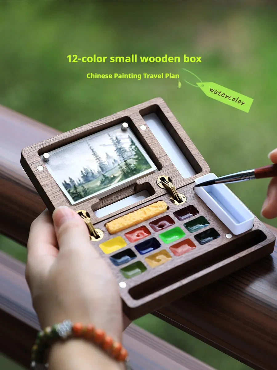 Mini walnut wood watercolour paint box open showing pigment colours inside with paint brush