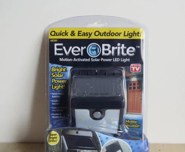 Set of four white solar-powered LED outdoor lights with motion sensors on stakes for garden or pathway.