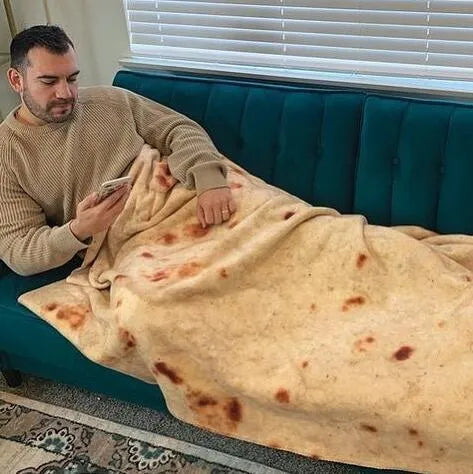 Round coral fleece burrito blanket with food print, shown in a folded pile.