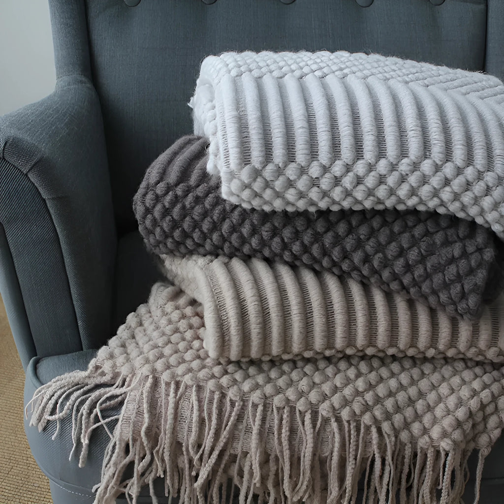 Small grey polyester nap blanket folded on a sofa, showing its size and texture.