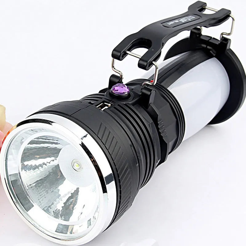 Black solar charging LED emergency flashlight with USB port on a textured surface.