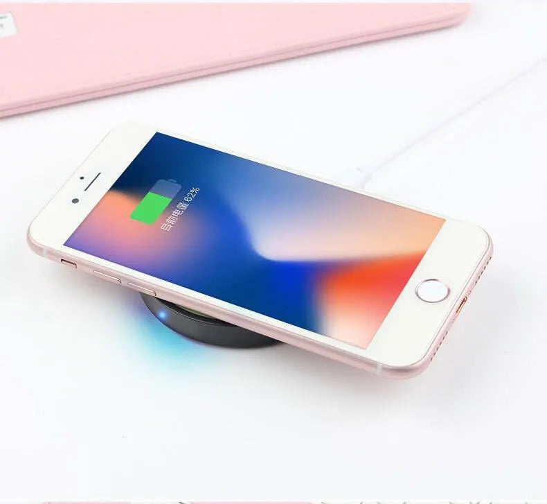 Compact round Qi wireless phone charger on a table in blue, next to a smartphone.