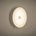 Small white circular motion sensing LED night light with USB charging port