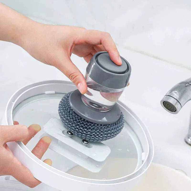 Kitchen palm brush with integrated push-type soap dispenser and bristles for scrubbing.