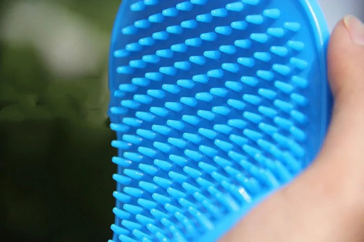 Oval rubber pet bath brush in hand for dog or cat grooming, red colour