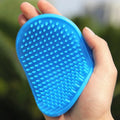 Oval rubber pet bath brush in hand for dog or cat grooming, red colour