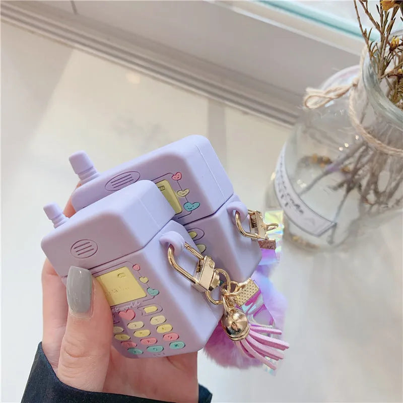 Purple silicone clamshell case for Apple AirPods with a small white fur ball pendant attached.