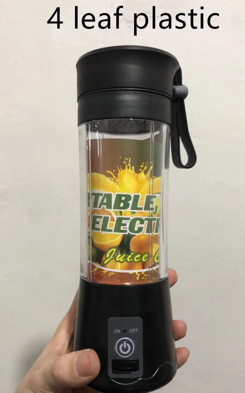 Mini USB electric fruit juicer with pink 400ml cup and stainless steel blades on a table.