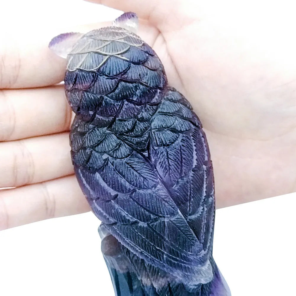 Purple fluorite hand-carved owl ornament on a wooden surface.
