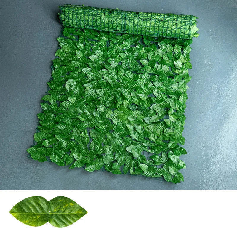 Artificial green plastic fence panel with printed leaves, used as a balcony privacy screen.