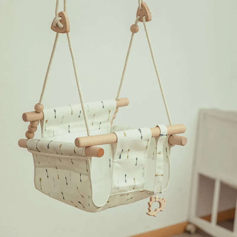 Natural cotton canvas baby swing chair with wooden seat and cushion hanging indoors