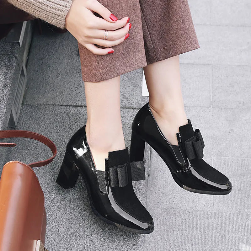 Women's black patent leather high-heel shoes with a thick heel and square toe.
