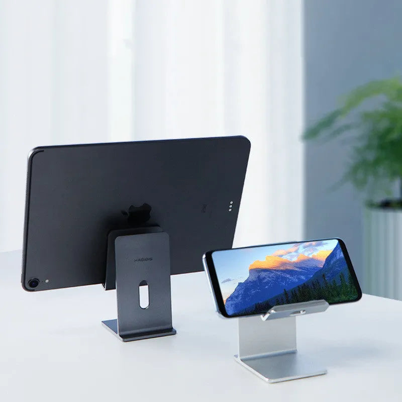 Dark space grey aluminium alloy mobile phone and tablet holder on a wooden desk.