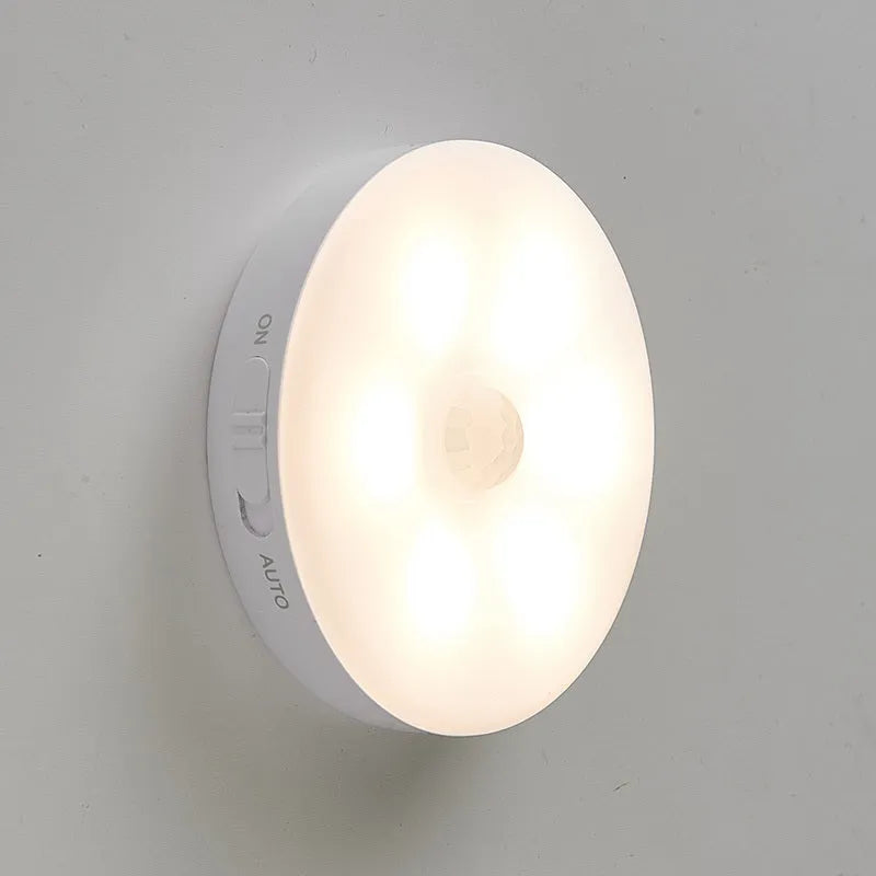 Two compact wireless motion sensor LED lights with adhesive backing, one illuminated with warm white light.