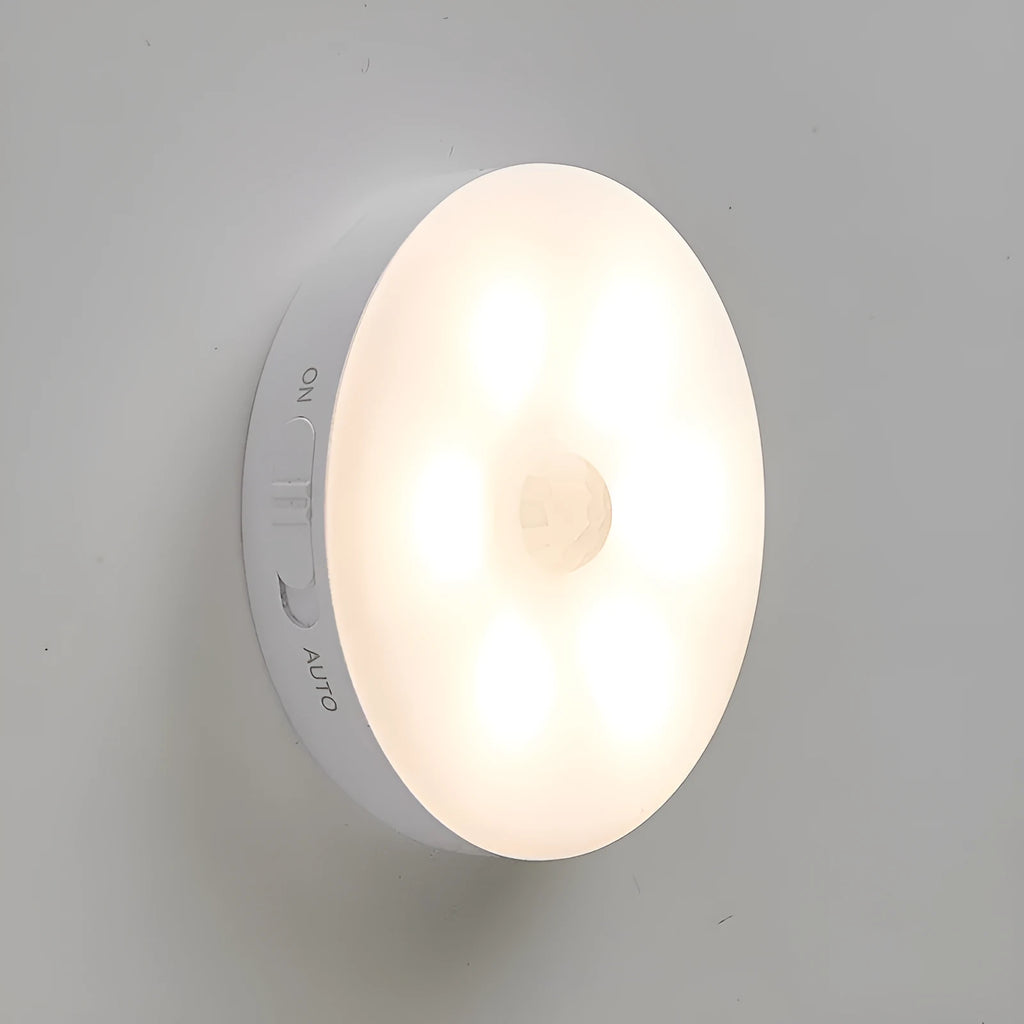 Two compact wireless motion sensor LED lights with adhesive backing, one illuminated with warm white light.