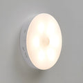 Two compact wireless motion sensor LED lights with adhesive backing, one illuminated with warm white light.