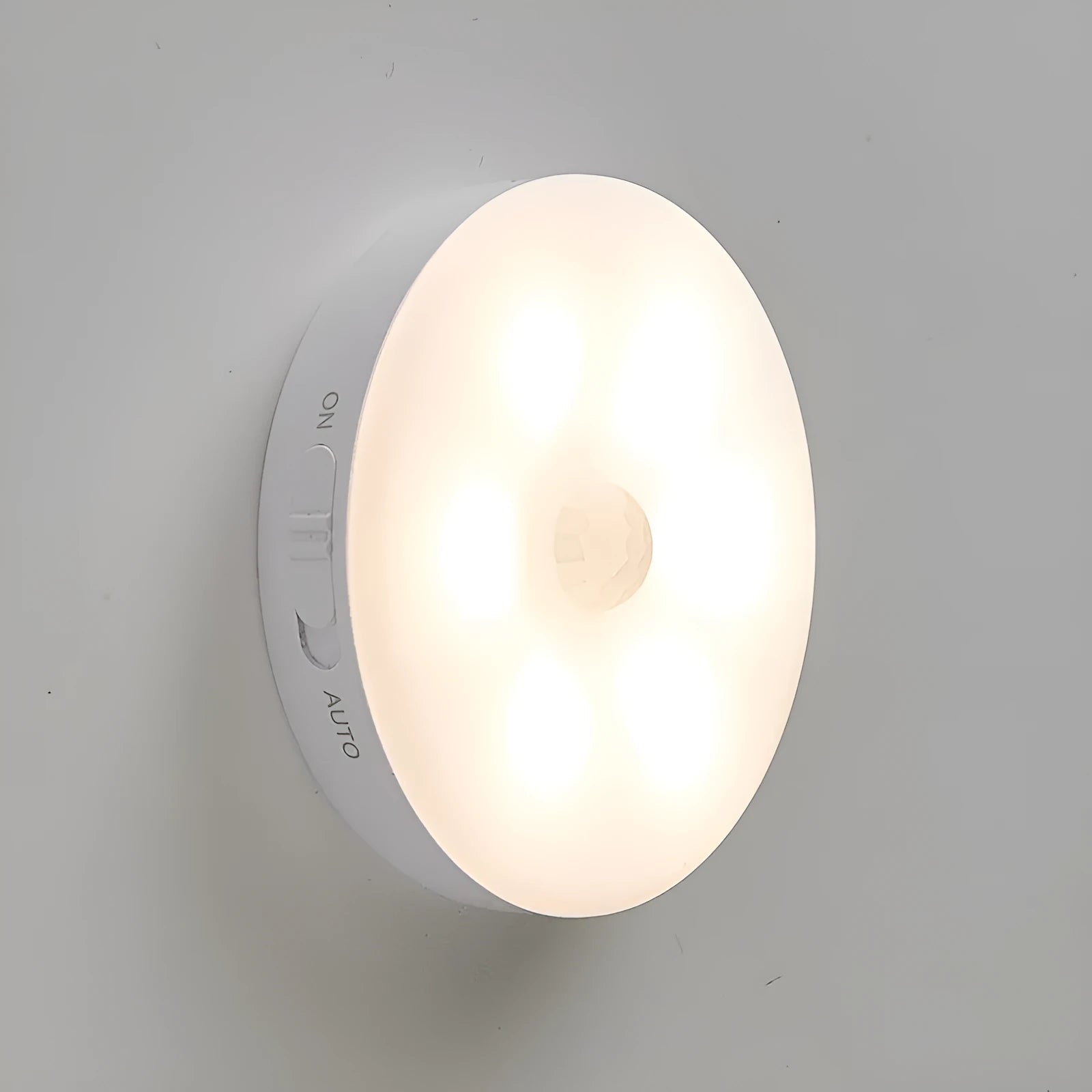 Two compact wireless motion sensor LED lights with adhesive backing, one illuminated with warm white light.