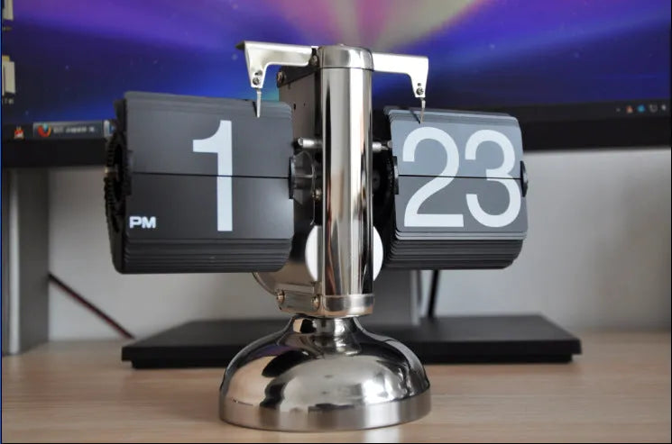 Small scale retro flip clock with black or white trim and black flip cards on a desk