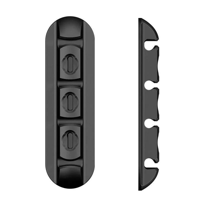 Black soft plastic magnetic desktop charging cable organiser on a desk.