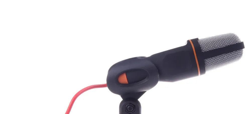Black wired PC microphone with attached metal clip holder on a desk.