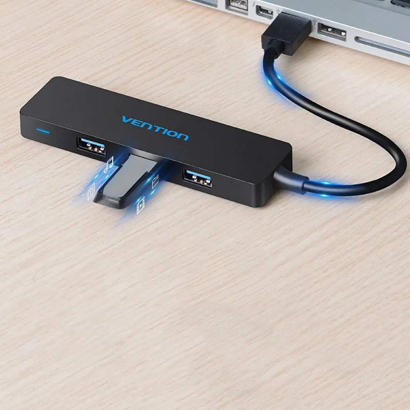 Black four-port USB 3.0 hub with a short cable on a desk.