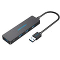 Black four-port USB 3.0 hub with a short cable on a desk.