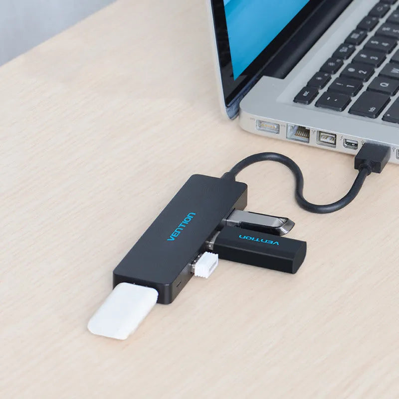 Black four-port USB 3.0 hub with a short cable on a desk.