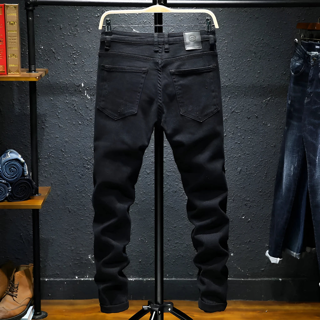 Men's black ripped stretch jeans with straight leg, distressed hand-painted details, and zipper front, shown on model.