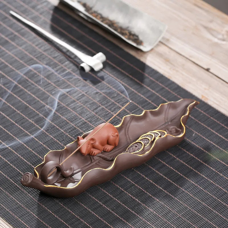 Purple clay ceramic lying incense burner with golden rat design holds incense stick