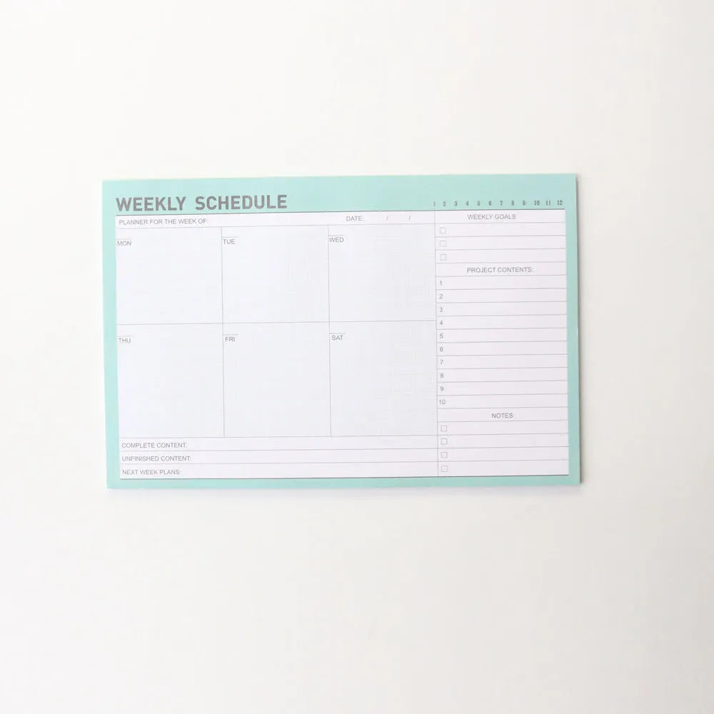 Domikee pink and green paper desk organiser planner notebook open on a desk.