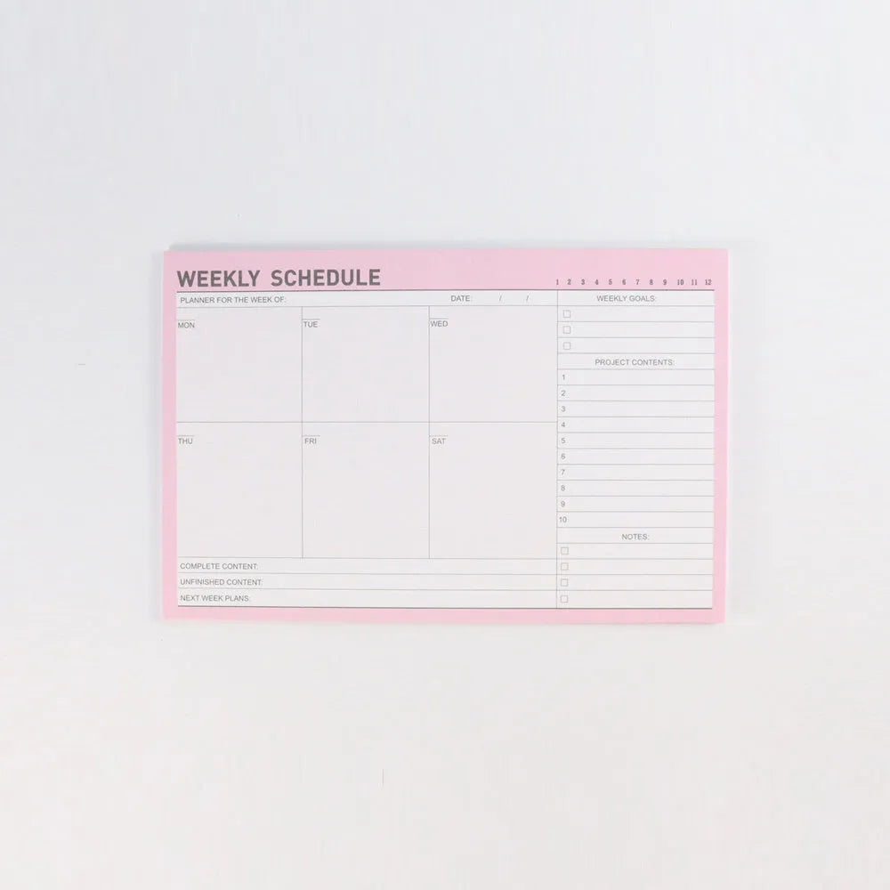 Domikee pink and green paper desk organiser planner notebook open on a desk.