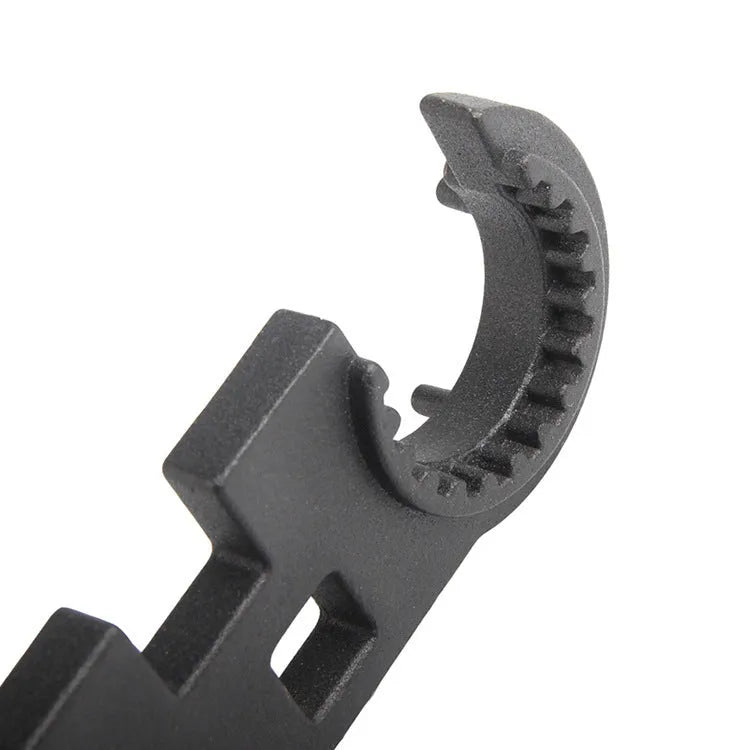Black all-steel dual-purpose combination wrench for AR-15 and M4 rifle maintenance on a workshop bench.
