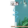 Blue universal mobile phone holder with bendable memory alloy hose on a wooden bedside table.