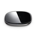Black circular 15W wireless charging pad with a glass top and zinc alloy rim on a desk.