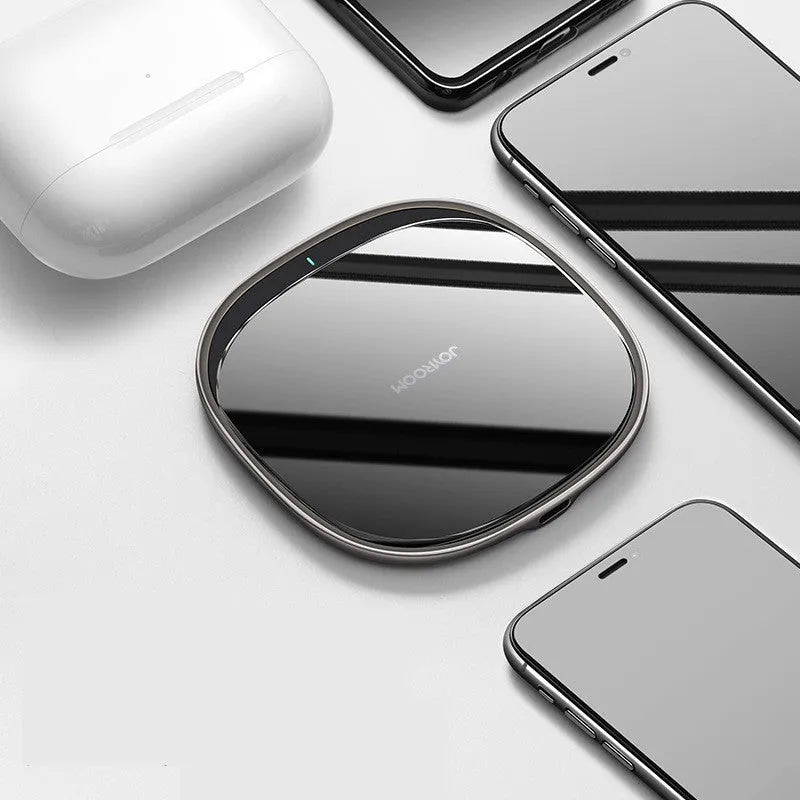 Black circular 15W wireless charging pad with a glass top and zinc alloy rim on a desk.