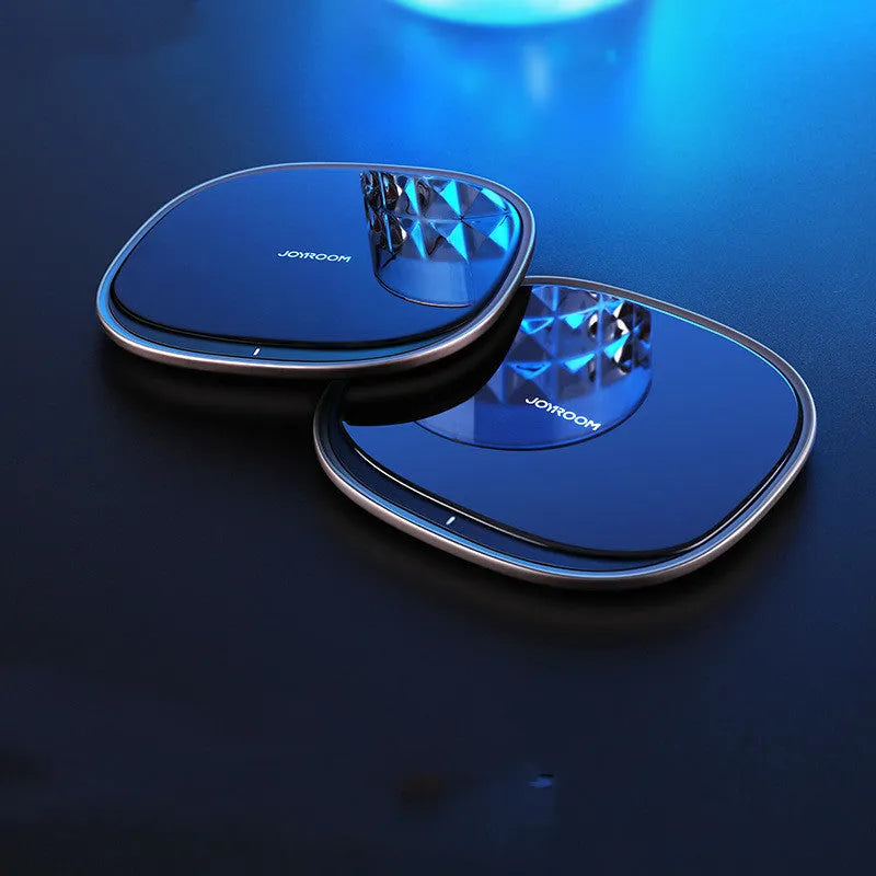 Black circular 15W wireless charging pad with a glass top and zinc alloy rim on a desk.