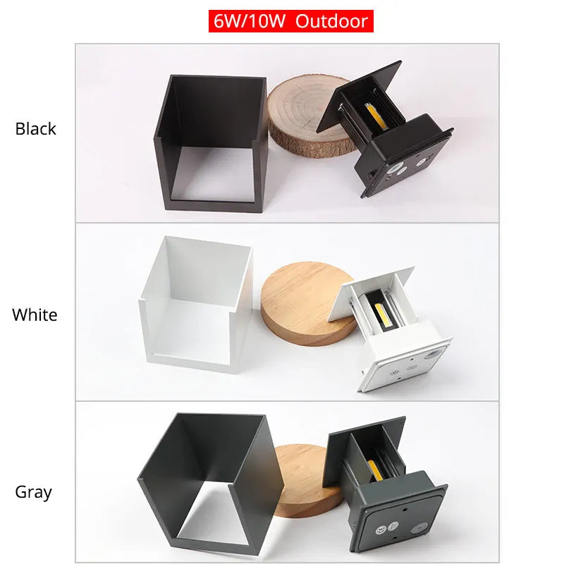 Square black aluminium wall lamp with 360-degree light output mounted on a corridor wall.