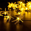 Five-metre solar-powered outdoor string lights with 30 warm white dragonfly-shaped LEDs and a separate solar panel on a spike.