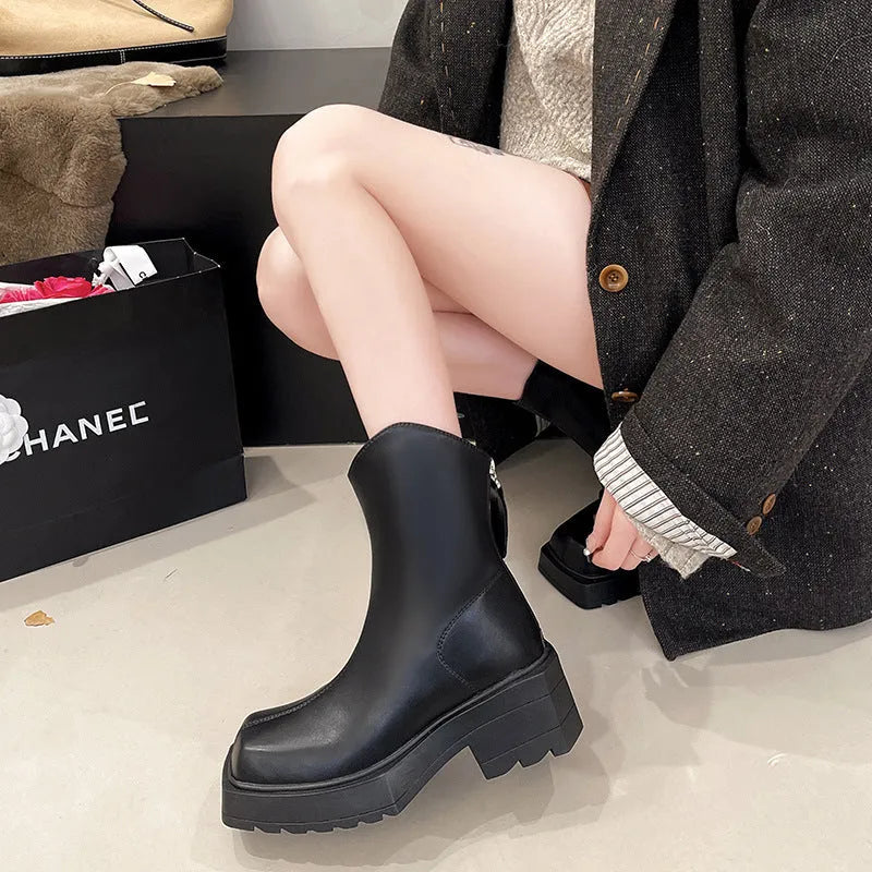 Women's black platform Martin ankle boots with a square toe and back zipper on a model.