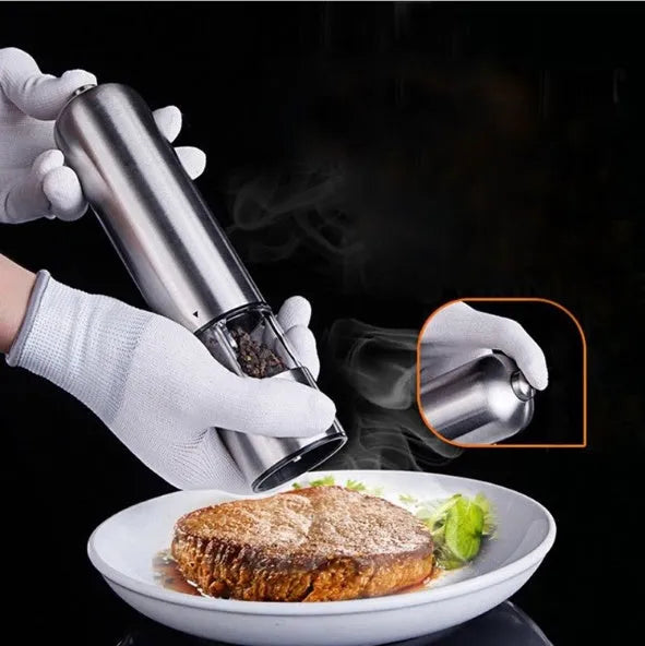 Tall stainless steel electric pepper grinder on a kitchen countertop.