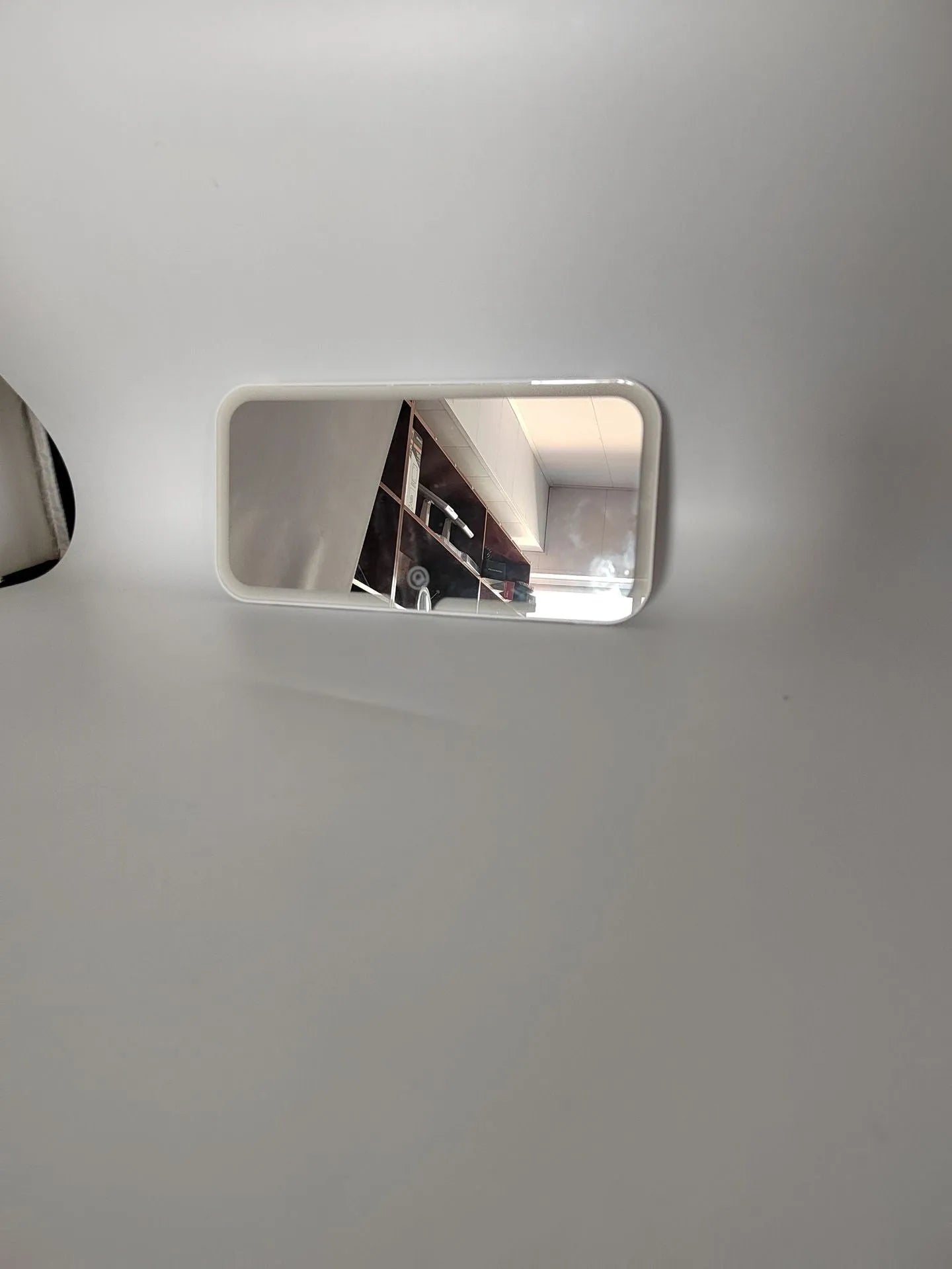 White car sun visor with rectangular LED-lit make-up mirror mounted on it.