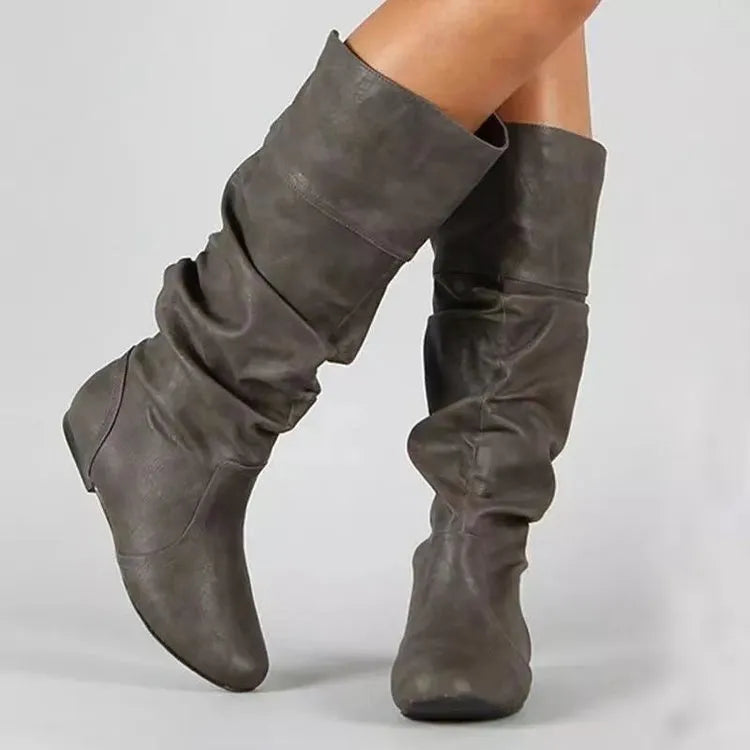 Women's flat knee-high slip-on boots in black with a round toe and rubber sole.