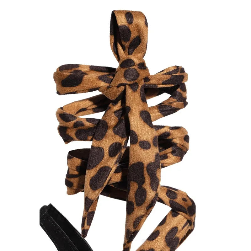 Light brown leopard print women's high heel sandals with crossover straps and a thin stiletto heel.