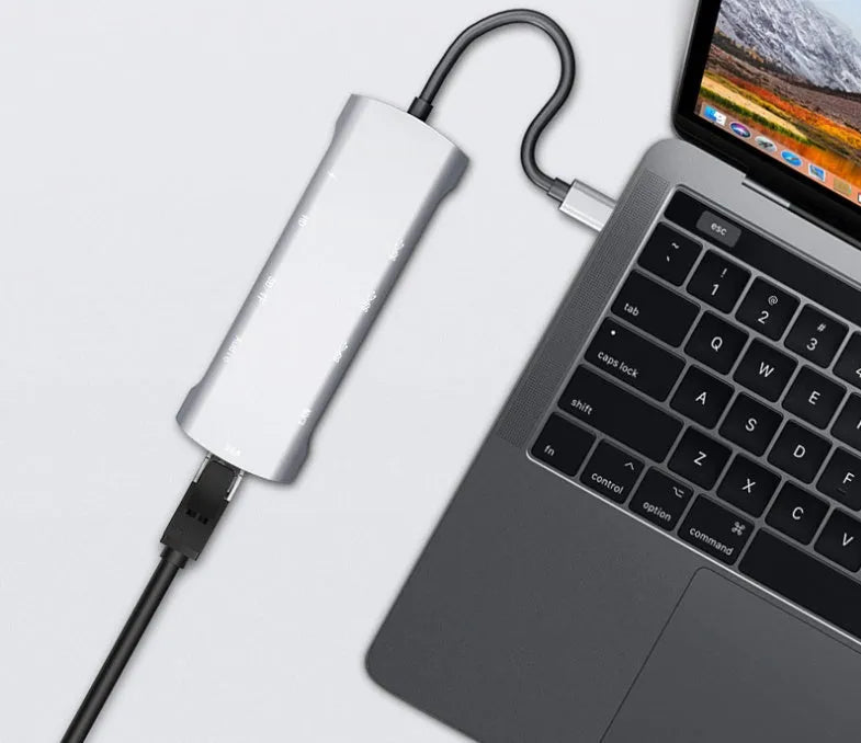 Grey aluminium USB-C docking station showing HDMI, VGA, USB, and charging ports.
