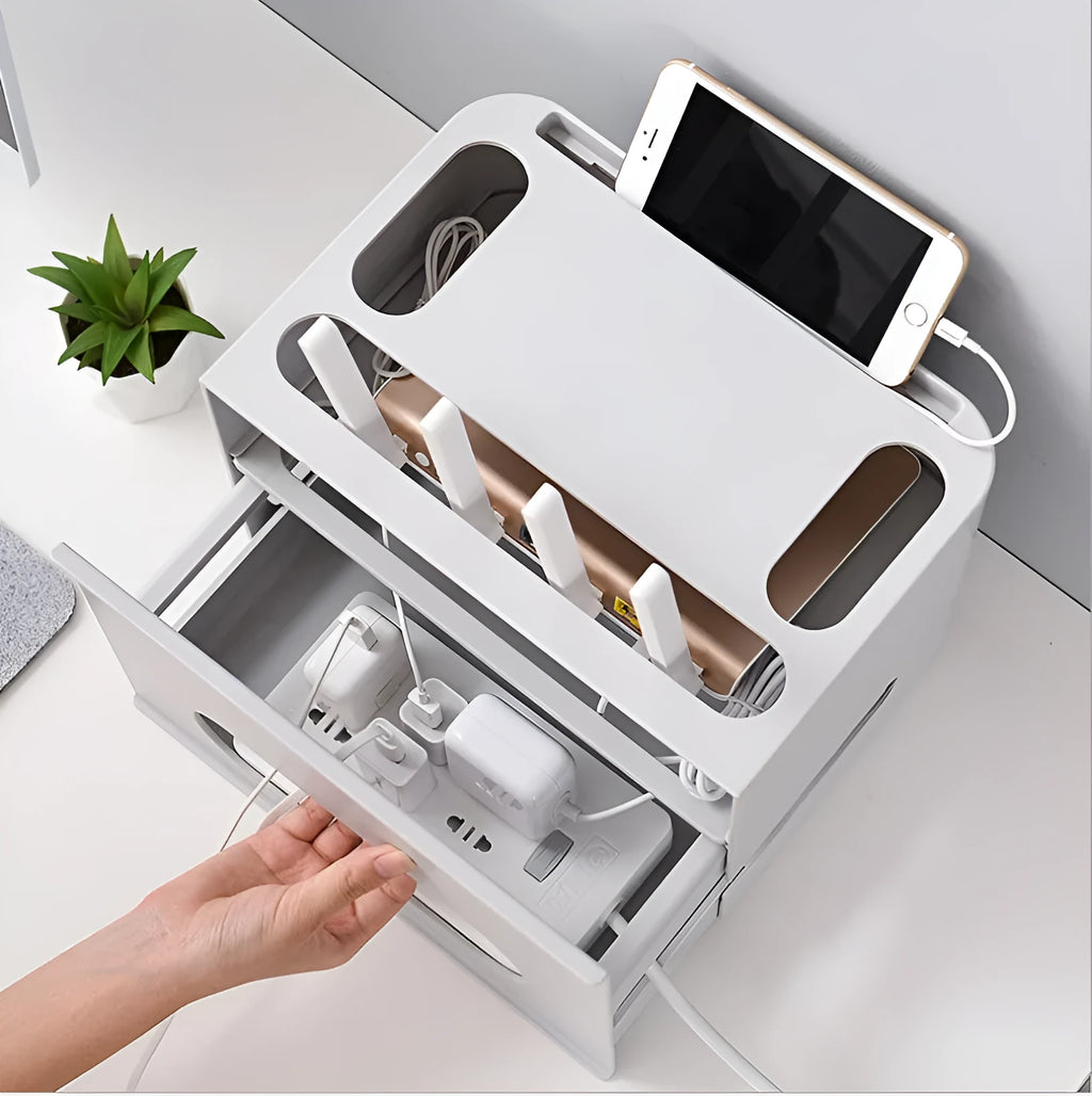 White plastic wireless router storage box with cable slots on a desk next to a router.